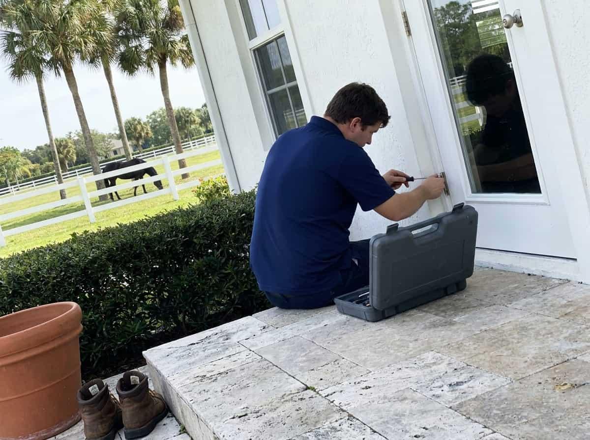 Technician servicing a back door lock at an equestrian property in Wellington, FL