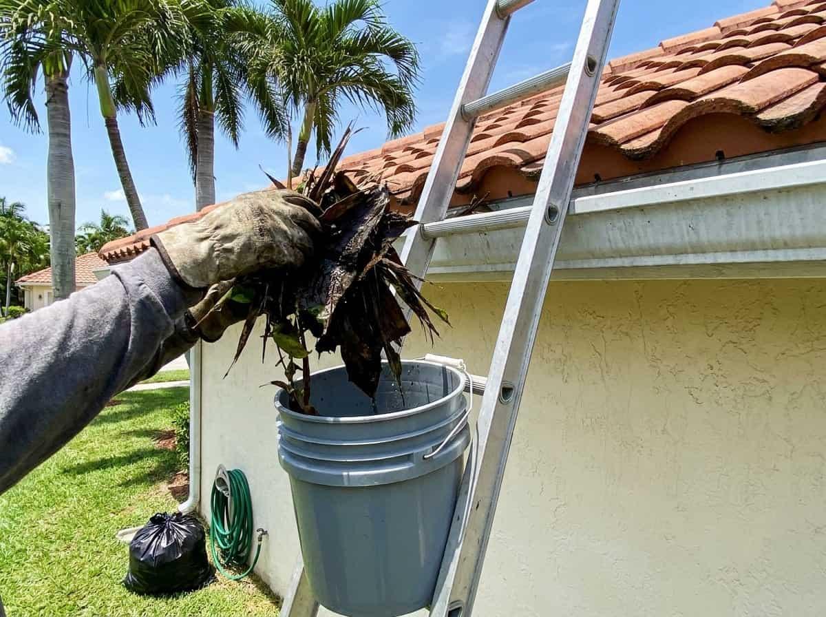 Gutter being cleared by hand at a single-story home in Palm Beach County, FL