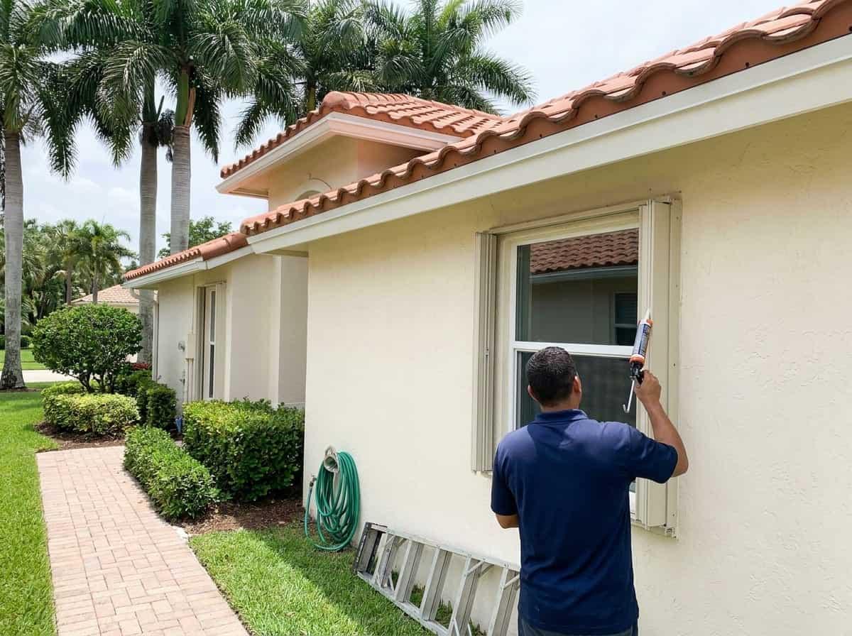 Sealing around a window frame on a freshly painted home in Greenacres, FL