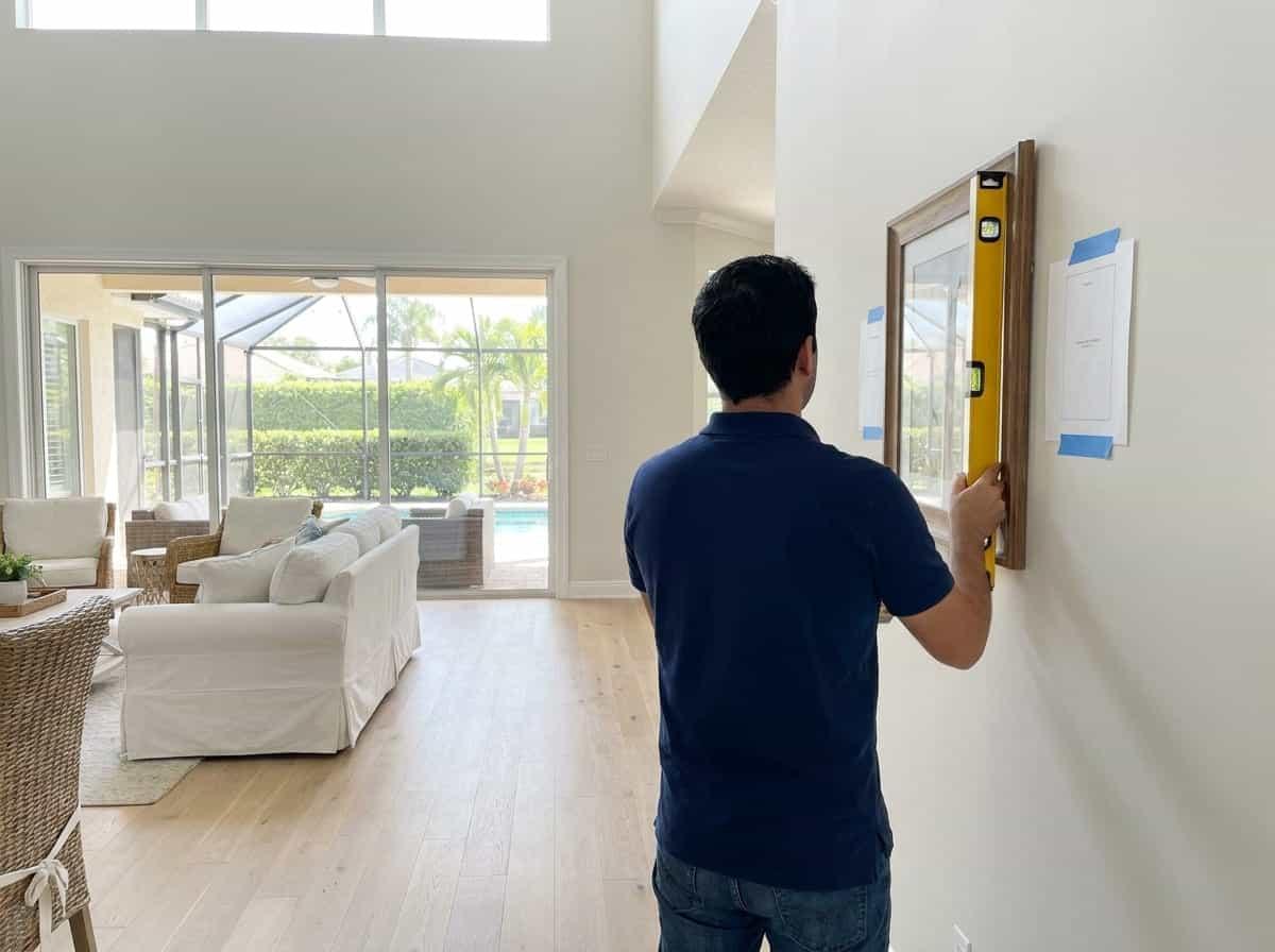 Framed art being hung and leveled in a home in Palm Beach County, FL