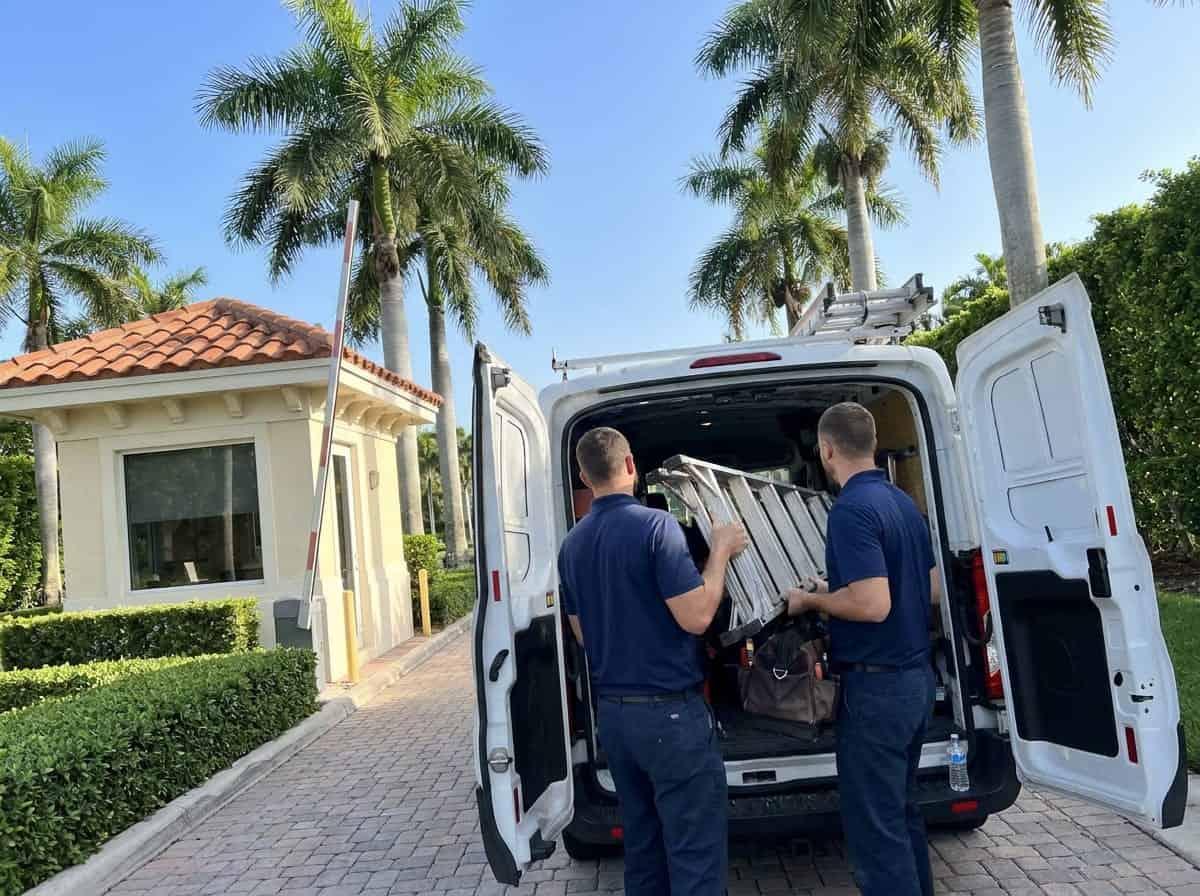 Two technicians unloading a work van inside a gated community in Palm Beach County, FL